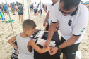 Policial civil coloca pulseirinha em braço de criança