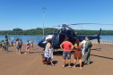 Diversas pessoas observando o helicóptero da Polícia Civil no litoral
