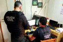 Policiais civis analisam computador no interior de um quarto