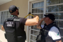 Policiais civis arrombando porta para investigação do local