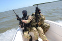 Policiais civis empunhando fuzis em barco da corporação