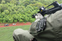 Policial civil em helicóptero apontando fuzil para abordagem terrestre