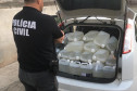 Policial observa garrafas com produto adulterado