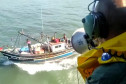 Policial civil em helicóptero alertando pescadores com megafone