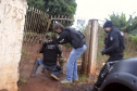 Policiais civis arrombando portão para entrar em residência de suspeito