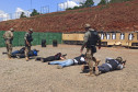 Policiais civis deitados, apontando as armas para alvos de papel, observados pelos instrutores