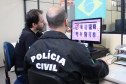 Policiais analisam digitais em monitor