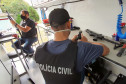Dois policiais civis fazendo manutenção de armas
