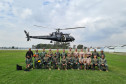 Participantes do treinamento posando para foto, tendo ao fundo o helicóptero