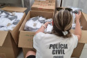 Policial civil verificando uniformes em diversas caixas abertas