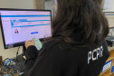 Policial civil ao computador, segurando RG