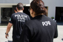 Três policiais civis entrando em delegacia
