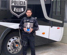 Investigador Juliano Filardo posa com drone e uniforme policial em frente a ônibus da PCPR