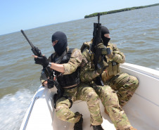 Policiais civis empunhando fuzis em barco da corporação