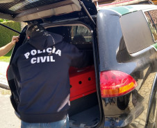 Policial civil acomodando caixa com cobra no interior da viatura