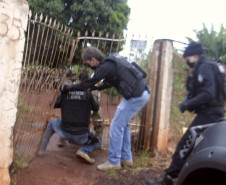 Policiais civis arrombando portão para entrar em residência de suspeito