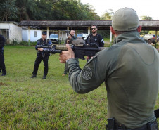 Policial civil apontando fuzil enquanto fala com alunos