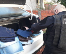 Policial civil com material apreendido, no porta-malas de um veículo