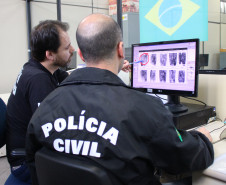 Policiais analisam digitais em monitor