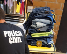 Policial civil, de costas, analisando mercadoria da loja