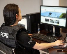 Policial civil feminina aparece acessando website da instituição em computador