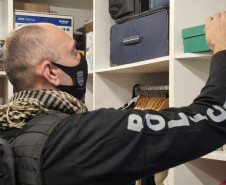 Policial civil procurando objetos em armário