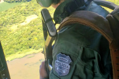 Policial civil armado observa litoral durante voo de helicóptero