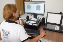 Policial civil ao computador, trabalhando no sistema de identificação