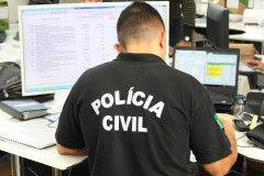 Policial civil sentado, em frente à computadores