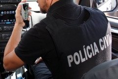 Policial civil no interior de uma viatura, falando ao rádio