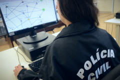 Policial civil sentada de costas utilizando o computador