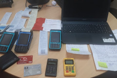 Máquinas de cartão, notebook, cartões de crédito e outros materiais sobre uma mesa.
