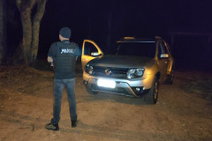 Policial civil ao lado de viatura descaracterizada, à noite