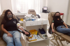 Duas policiais civis sentadas, doando sangue