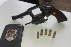 Arma, munições e carteira da polícia sobre uma mesa