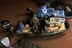 Policial civil no interior de um barco, com material apreendido