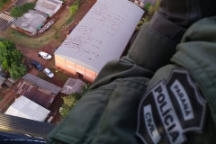 Policial civil sobrevoando o local, de helicóptero