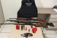 Armas, munição apreendida e colete da polícia, sobre uma mesa