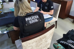 Policiais civis à mesa, preenchendo documentos