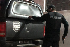 Policial civil empunhando arma e fechando tampa do porta-malas de viatura