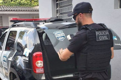 Policial civil fechando tampa do porta-malas de viatura