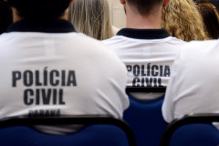 Policiais civis de costas, sentados, recebendo instruções