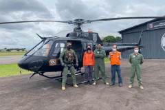 Policiais civis e membros da defesa civil posando para fotografia ao lado de helicóptero