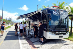 Onibus com delegacia móvel estacionado no litoral e vários policiais civis à disposição para atender a população