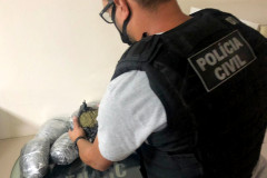 Policial civil abrindo pacote de skunk sobre uma mesa