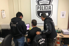 Três policiais civis analisam imagem na tela do computador