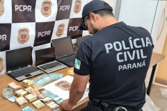 Policial civil organiza sobre uma mesa dinheiro recuperado