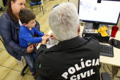 Policial civil recolhendo impressão digital de criança