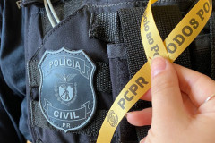 Policial civil segura fita proximo a escudo em uniforme 