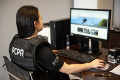 Policial civil feminina aparece acessando website da instituição em computador
